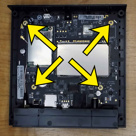 The four Phillips screws (one in each corner) securing the board — lift it to reach the FLASH USB port and Recovery button